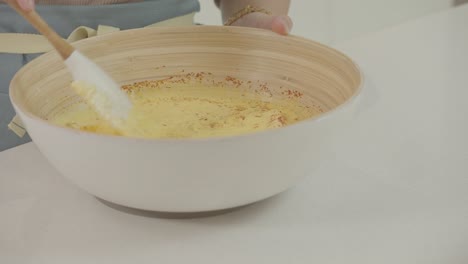 la vista de cerca de las manos femeninas golpea la mantequilla en el bol con otros ingredientes en la cocina