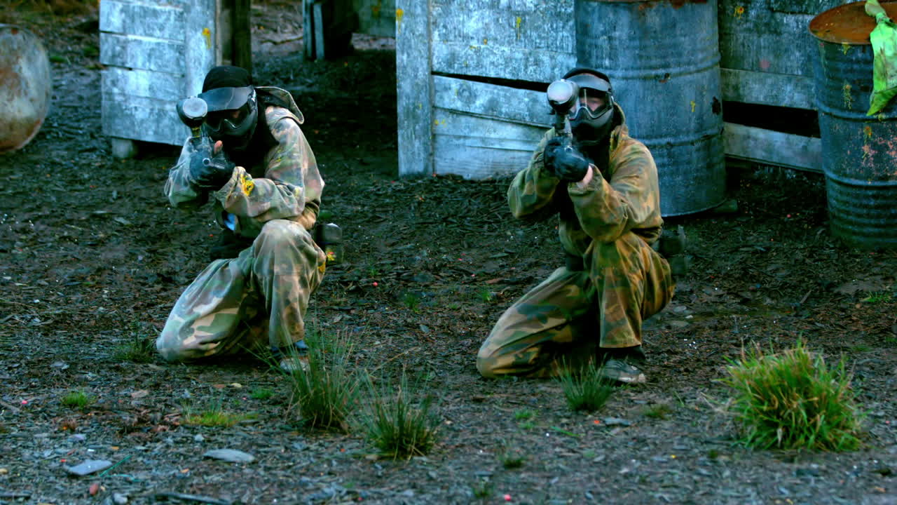 equipo disparando sus armas de paintball arrodillado