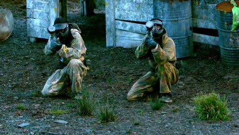 equipo disparando sus armas de paintball arrodillado