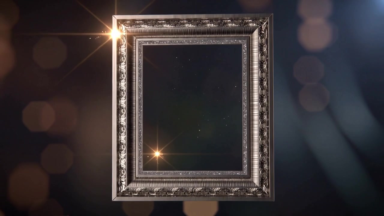Vznášející se zdobený kovový rám se otáčí do záběru v tmavém studiu, odhaluje hvězdný panel a záblesky.