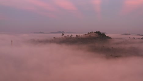 aerial view above the mist to see a magic sunrise with blue and pink colors and ray of sunshine behind mountains