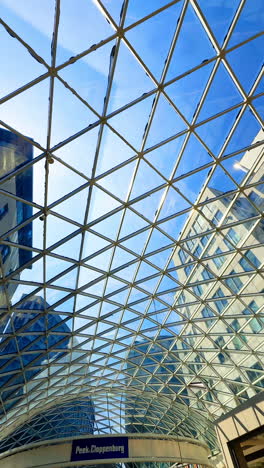 glass structure in modern design. a striking view showcases a geometric glass ceiling connecting modern buildings under a clear blue sky