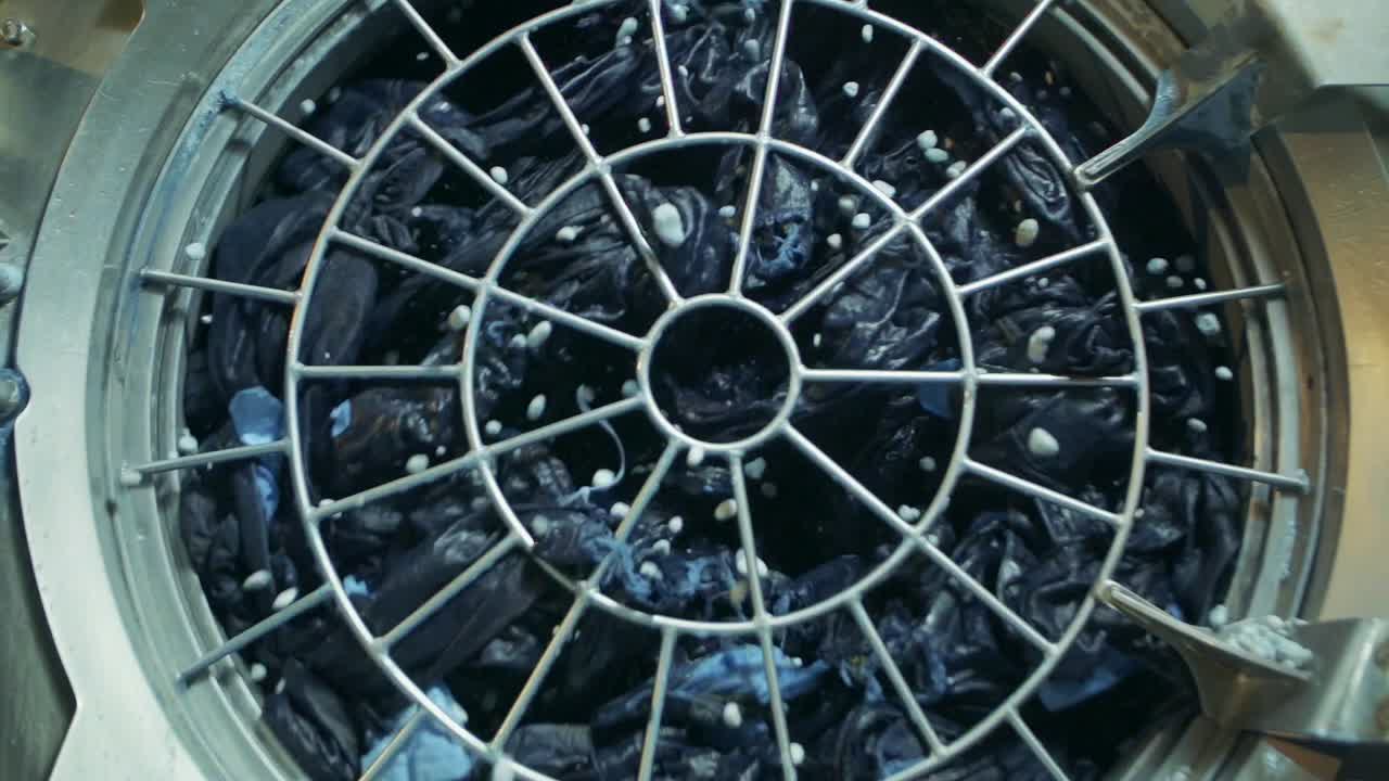 청바지 공장에서 청바지는 산업용 세탁기에서 경석으로 세탁됩니다.