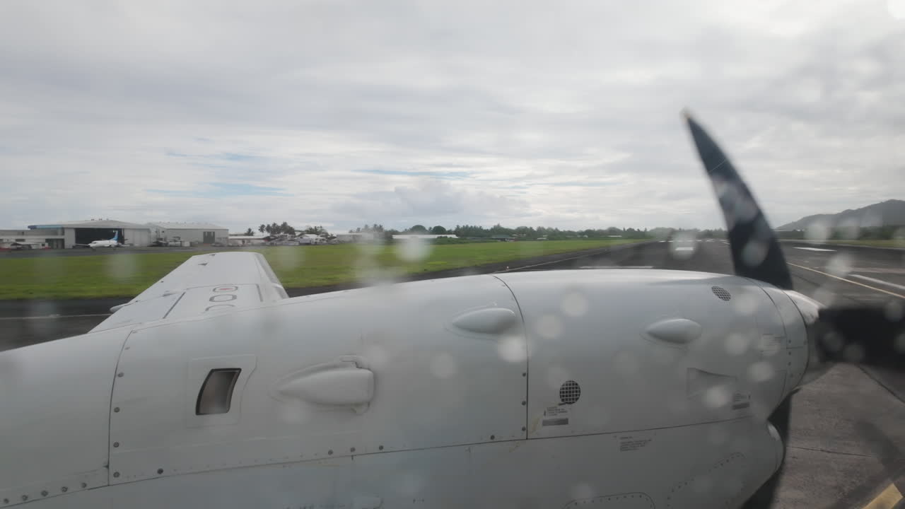 Raindrops on window, inside airplane looking out at wing and propellor over Cook Islands Rarotonga