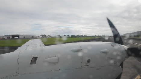 raindrops on window, inside airplane looking out at wing and propellor over cook islands rarotonga