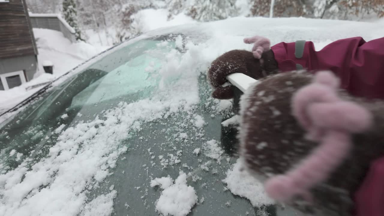 persona raspando hielo del parabrisas del coche en invierno usando un raspador