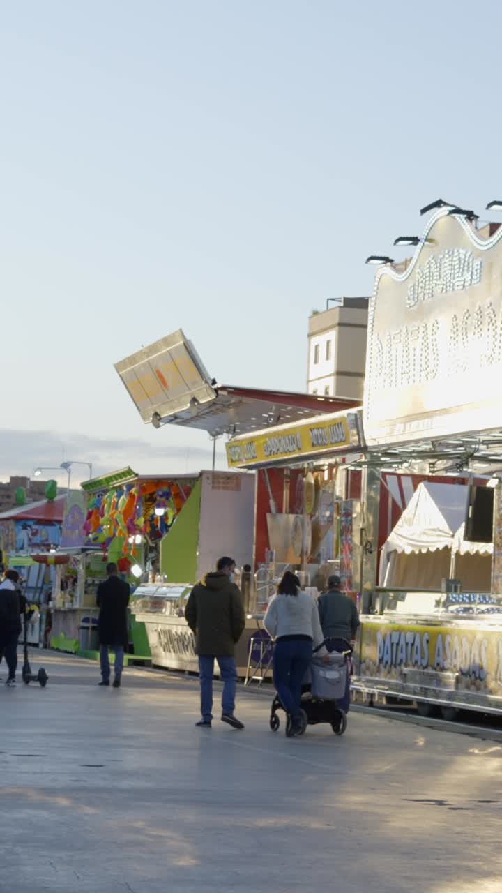 People walking past food stalls at an outdoor fair or market