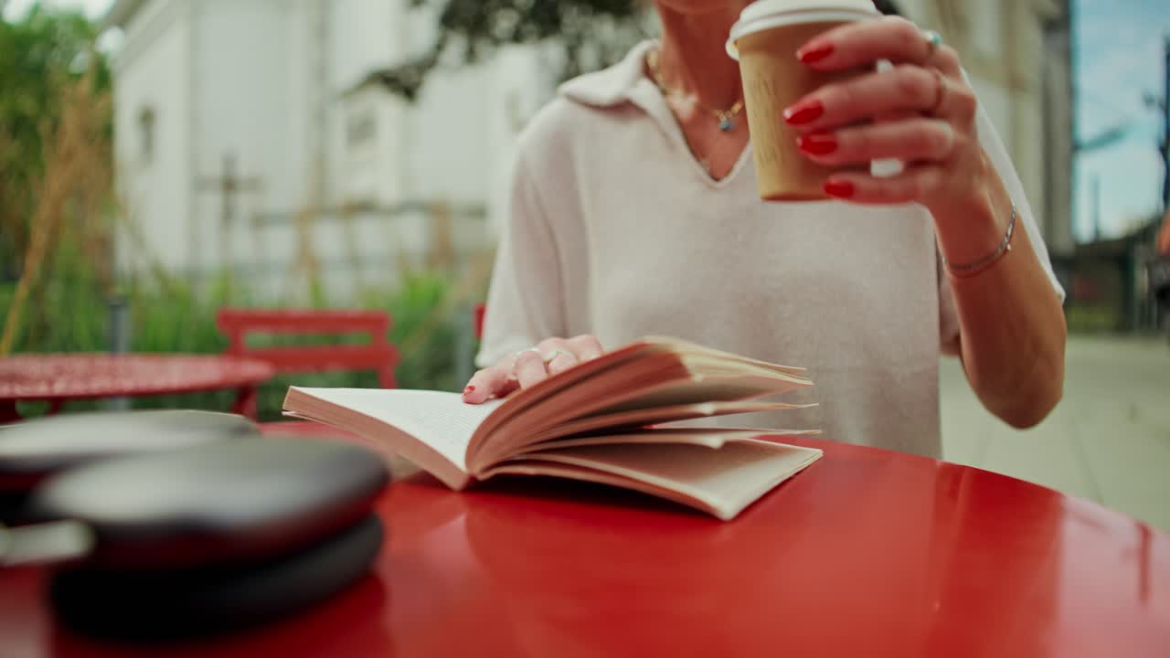 Mulher lendo um livro e bebendo café em um café ao ar livre
