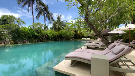 row of empty sun loungers beside swimming pool in luxury resort in kuta, lombok