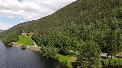 flying parallel with a road next to the forrest. small farm nearby