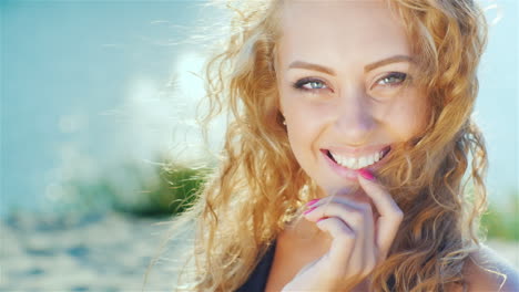 close-up of a beautiful young woman smiling at the camera sunny day at the beach near the sea