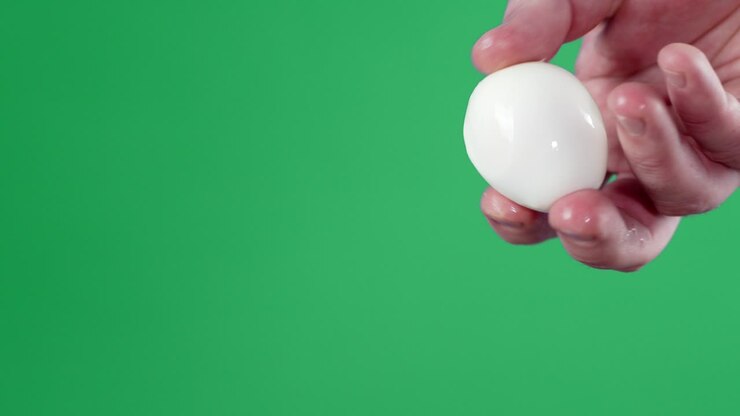 The man's hand holds a boiled egg.