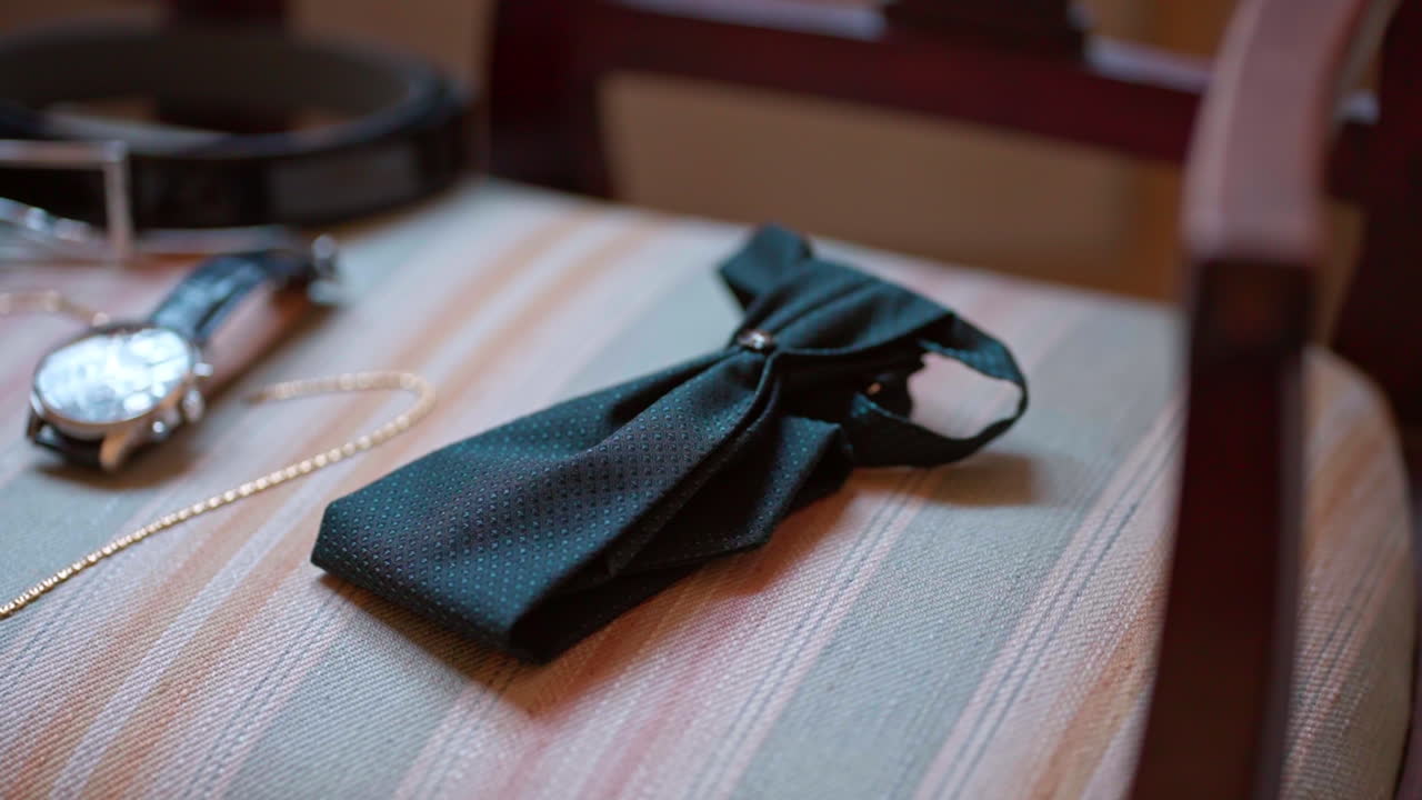 Bow tie, watch, and belt lay on chair, elegant style and formal setup