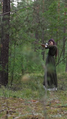 young girl takes aim and shoots crossbow in summer forest