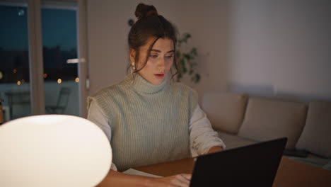 mujer de negocios tardía enviando mensajes de texto navegando por la computadora por la noche en el lugar de trabajo remoto de cerca