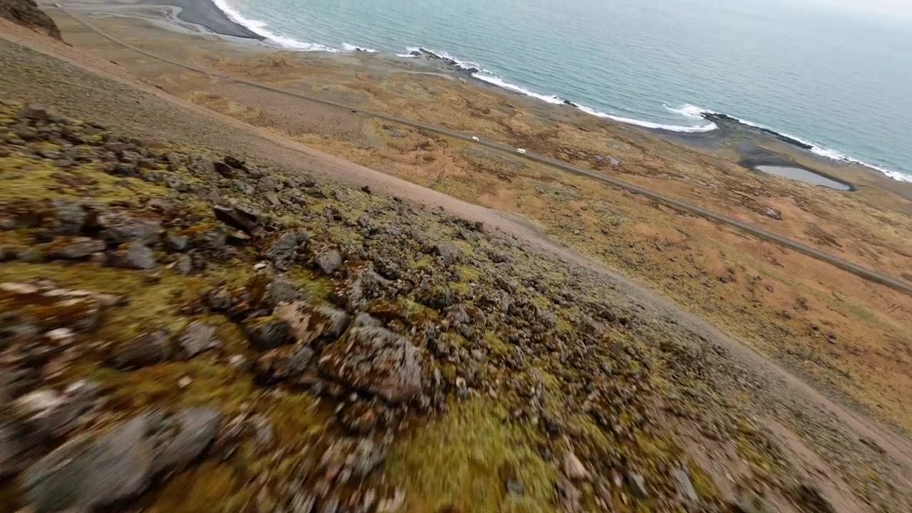 Un drone FPV scivola giù per scogliere vulcaniche coperte di nebbia in Islanda, rivelando aspre scarpate di basalto, pendii coperti di muschio, terreno costiero nero e l'Atlantico settentrionale durante una rapida discesa