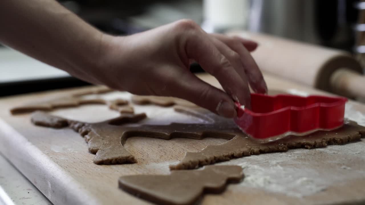Caucasian woman dusting gingerbread dough with flour and cutting out tree shape