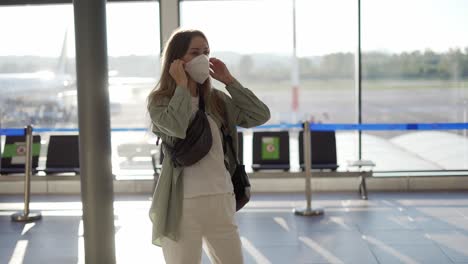 Female-traveller-putting-on-protective-mask-standing-at-the-airport