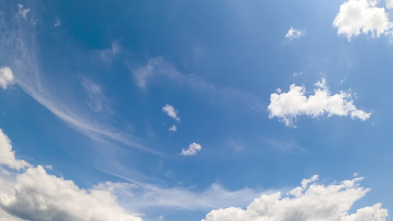 Beautiful blue summer sky with white clouds moving slowly. Soft fluffy cloudscape changing shape from low angle view.