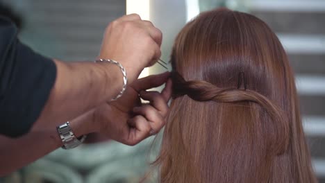 parrucchiere che crea un'acconciatura per la sposa in salone utilizzando il fissaggio con lacca spray - rallentatore 120 fps