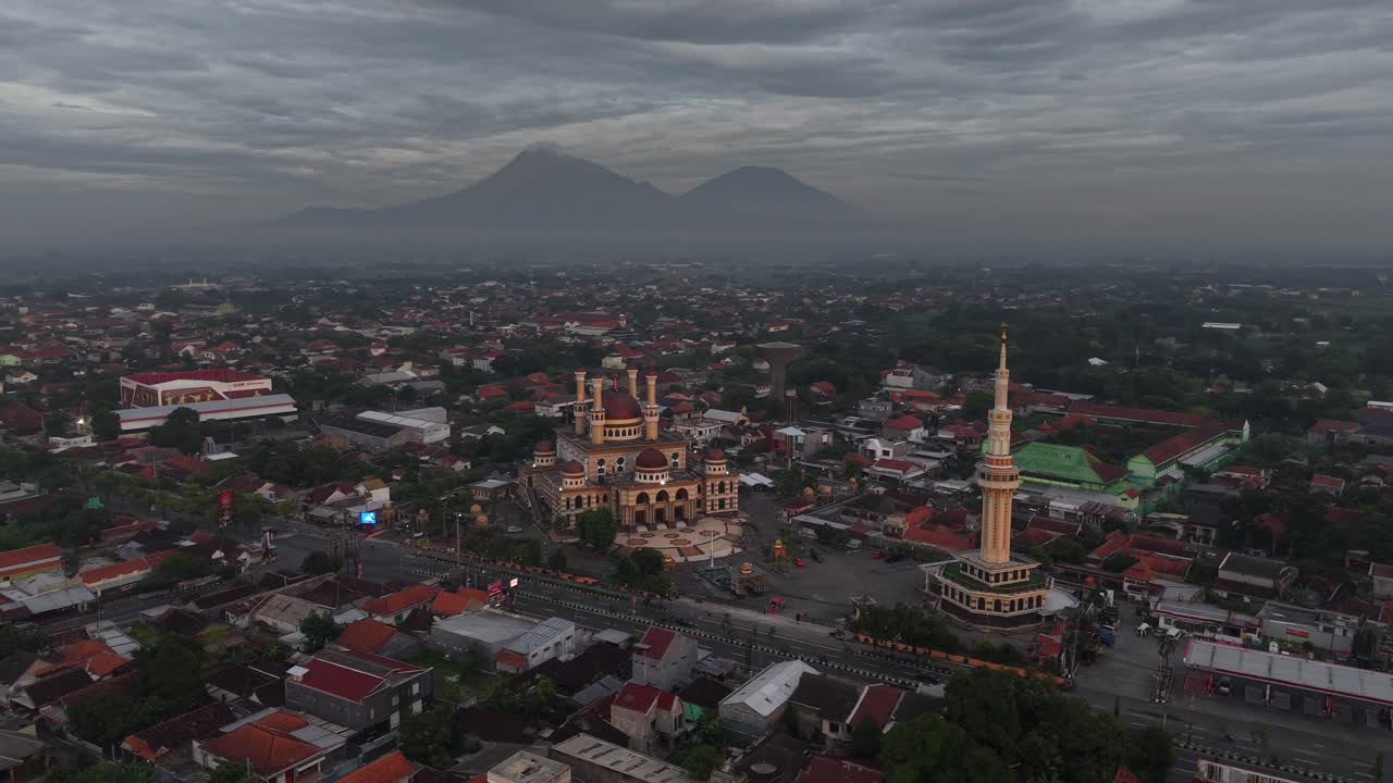 Rekaman udara saat matahari terbit di sekitar Masjid Al Aqsa yang megah dan mempesona di Klaten, Indonesia, dengan Gunung Merapi dan Gunung Merbabu di latar belakang