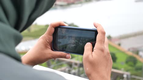 woman taking photo of cityscape with smartphone