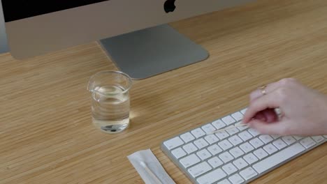 a person collects bacteria samples from a keyboard using a petri dish in a well-lit laboratory setting