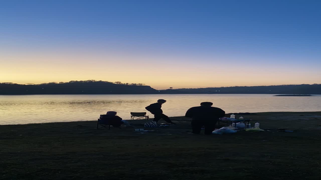 vertical timelapse footage, hanging out with friends by the lake while watching the sunset.