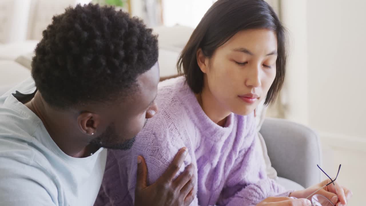 슬픈 다양한 커플이 소파에 앉아 거실에서 이야기하고 있습니다.