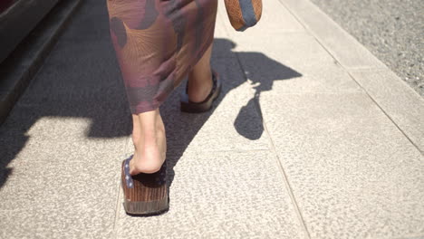 chico usando un yukata usando sandalias de madera tradicionales caminando hacia un templo en kyoto, japón iluminación suave