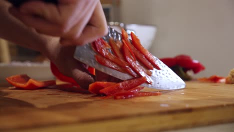 el chef corta pimiento rojo grande en la tabla de cortar, en la cocina