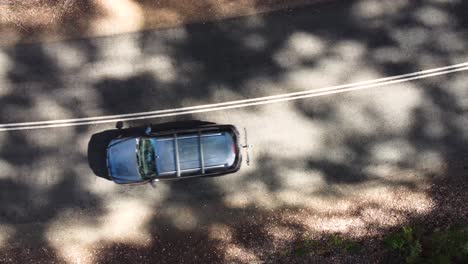 Birdseye-view-of-a-car-driving-along-a-beautiful-forest-road,-close-up