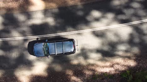 vista de pájaro de un automóvil que conduce a lo largo de un hermoso camino forestal, de cerca