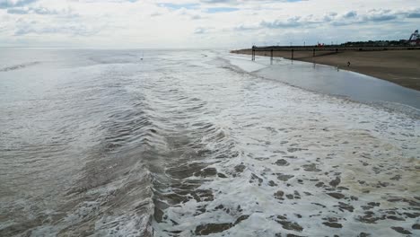 Typical-English-seaside-resort,-shot-using-a-drone,-giving-a-high-aerial-viewpoint-showing-a-wide-expanse-of-sandy-beach-with-a-pier-and-crashing-waves-8