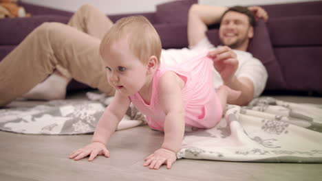 little baby want crawling on floor. daddy playing with daughter at home