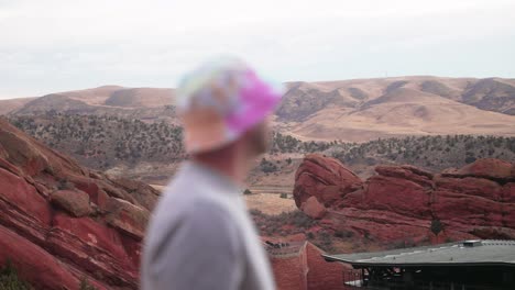 rack focus from red rocks park and amphitheatre to young caucasian male with round bucket hat 420 friendly