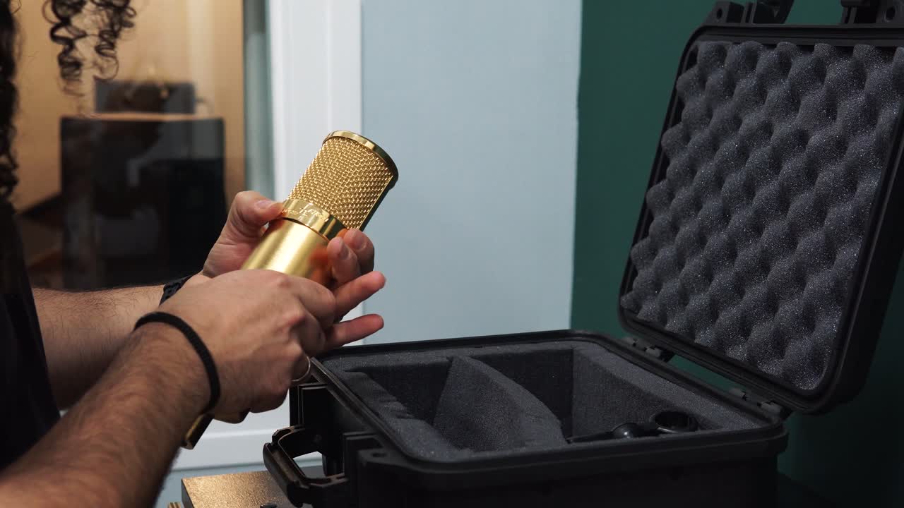 Primo piano di un uomo che tiene in mano una custodia sagomata per microfono dorato con schiuma