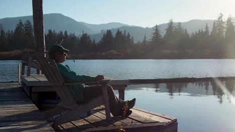 man sitting on dock at sunset