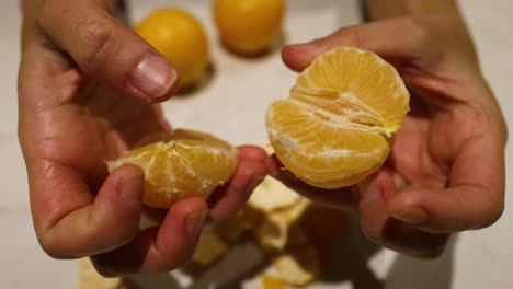 Hands peeling and splitting an orange