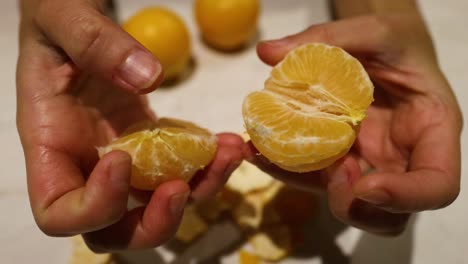 hands peeling and splitting an orange