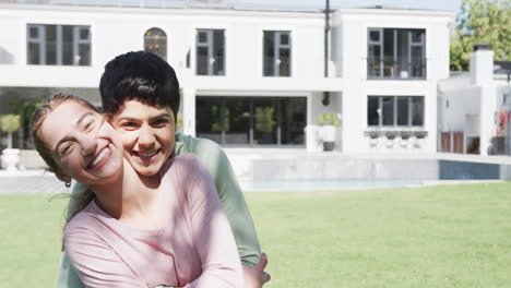 Feliz-Pareja-De-Lesbianas-Caucásicas-Abrazándose-Y-Sonriendo-En-Un-Jardín-Soleado,-Cámara-Lenta