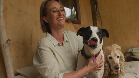 smiling senior caucasian woman playing with her two dogs at home