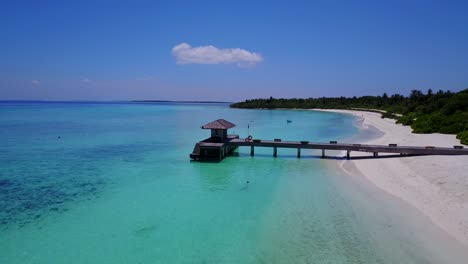 Aerial-descending-towards-water-on-beautiful-Maldives-island-resort,-4k