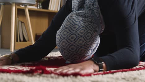 muslim woman wearing hijab at home kneeling on prayer mat and praying 1