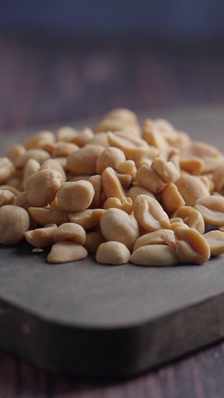 Close-up of Roasted Shelled Peanuts Piled on a Dark Surface
