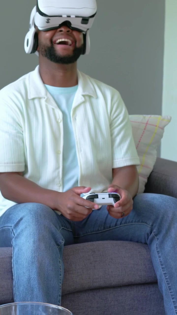 Vertical video: Turning man wearing VR headset holding controller and reacting to VR scene at home
