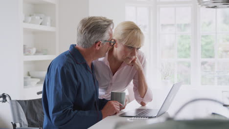 pareja de ancianos con un hombre en silla de ruedas buscando información sobre medicamentos en línea usando una computadora portátil