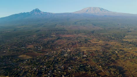 Amanecer:-Paisaje-De-Kenia-Con-Un-Pueblo,-Kilimanjaro-Y-El-Parque-Nacional-De-Amboseli---Seguimiento,-Vista-Aérea-De-Drones