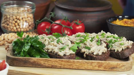 israeli cuisine. sprinkling parsley on forshmak on black rye bread close-up. national jewish herring dish, middle eastern culture. traditional snack vorschmack made of fish fillet