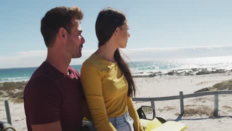 happy caucasian couple sitting in beach buggy by the sea talking